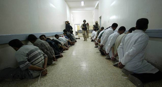 A soldier with the Iraqi 36th commando battalion, center, stands guard over detainees after Iraqi troops and U.S. special forces secured a hospital less than a mile from downtown Fallujah, Iraq, on Sunday, November 7, 2004. (Photo: Shawn Baldwin / The New York Times) 